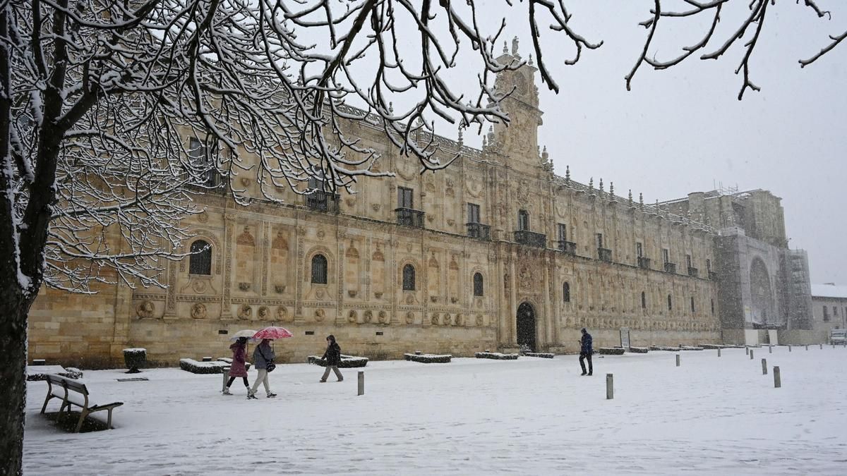 Varias personas junto al Parador de León, caminan entre la nieve caída este miércoles en León.