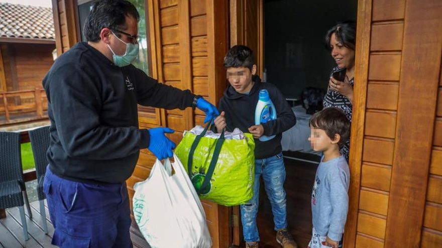 Un trabajador reparte comida a personas de origen latinoamericano en el complejo La Cigüeña de la localidad madrileña de Arganda del Rey, que ha empezado a recibir ciudadanos de origen Venezolano, Peruano y ecuatoriano en sus instalaciónes hoteleras, puestas a disposición del Gobierno en solidaridad con colectivos afectados por la crisis sanitaria a consecuencia de la pandemia mundial del COVID-19..