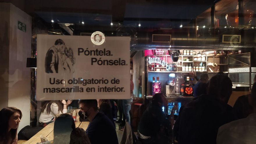 Un local de la calle Ponzano, con una advertencia en el cristal. Dentro solo una persona lleva mascarilla.