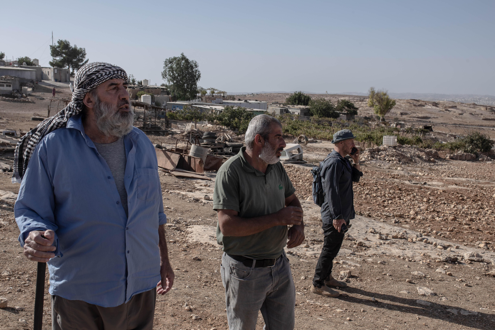 Dos residentes de Haribat al Nabi (izq) y un activista israelí miran a los colonos que se alejan tras el ataque.