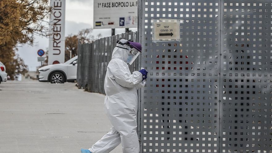 Un sanitario a los alrededores de la fila de vehículos para realizarse una prueba PCR de detección del coronavirus a las puertas del Hospital de Campaña próximo al de La Fe, en Valencia.
