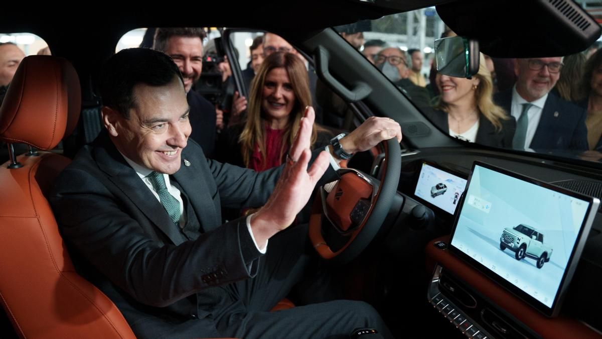 El presidente de la Junta de Andalucía, Juanma Moreno, saluda desde el interior de un coche en una visita a la fábrica de Santana Motor.