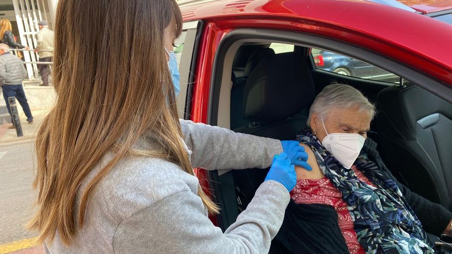 Una sanitaria inyecta una dosis de la vacuna contra la COVID-19 a las puertas de un centro de salud valenciano a una mujer sin bajar del coche.
