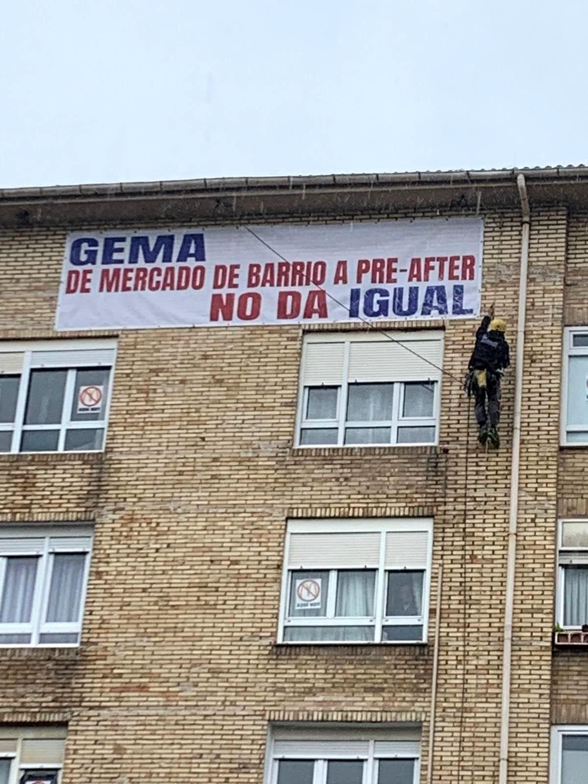 Un especialista realizando una retirada 'simbólica' de la pancarta bajo una intensa lluvia.