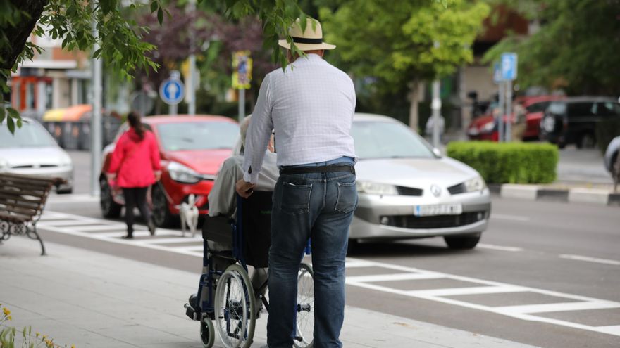 Un hombre pasea a una persona de edad avanzada en silla de ruedas durante su franja horaria permitida en la desescalada por la crisis del Covid-19 donde aquellos mayores de 70 años pueden salir a la vía pública de 10.00 a 12.00 horas y de 19.00 a 20.00 horas. En Madrid, (España), a 7 de mayo de 2020.