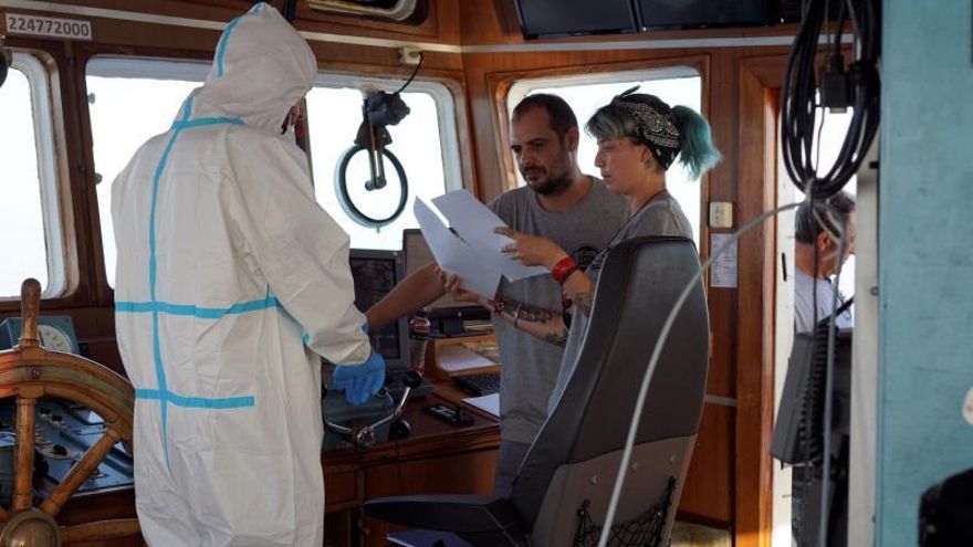 Agentes del ministerio de Salud de Italia entregan documentación este domingo a los responsables del buque "Open Arms" tras la inspección médica que realizaron en el badrco anclado frente a la costa de Lampedusa (Italia).