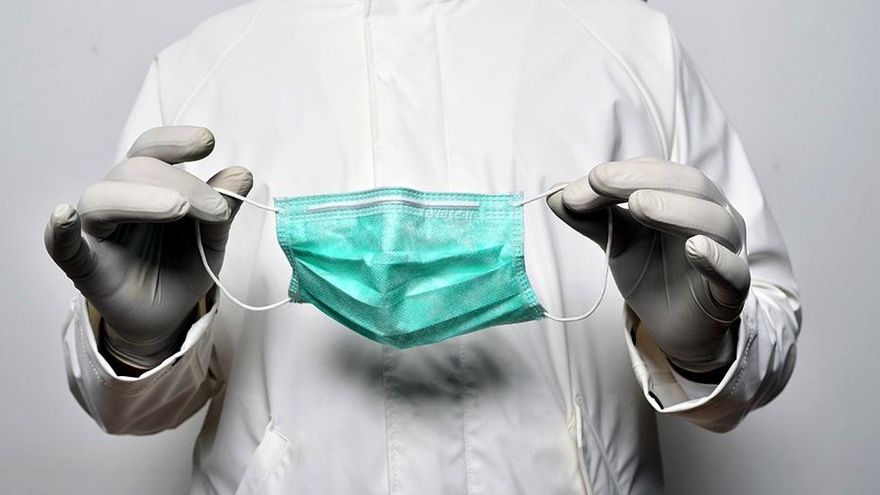 Archivo - Un médico sostiene una mascarilla en sus manos