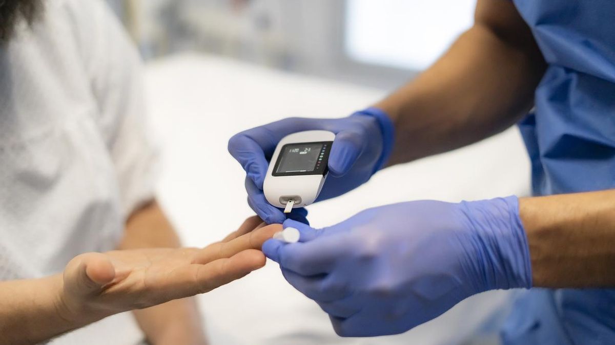 Un médico mide el nivel de glucosa en sangre del paciente en consulta.