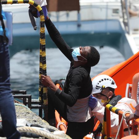 Una persona recibe ayuda para subir al muelle de Arguineguín desde una embarcación de Salvamento Marítimo.