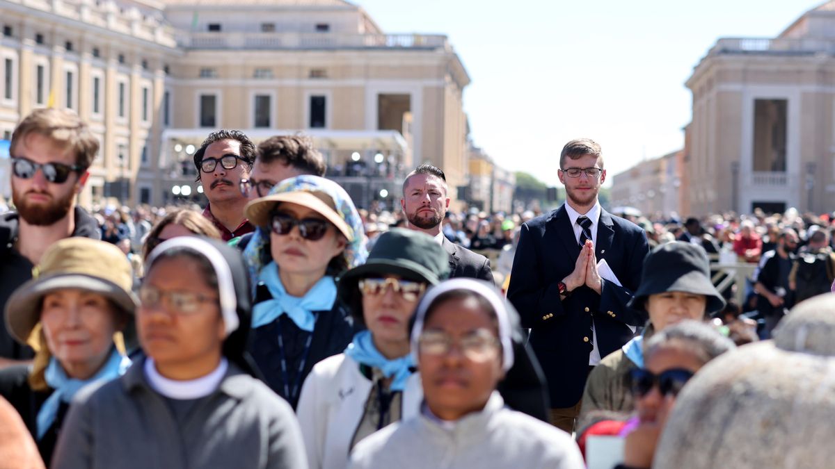 Unas 400.000 personas han despedido al papa en la plaza de San Pedro y las calles aledañas. En la imagen, varias personas rezan mientras escuchan la misa exequial.
