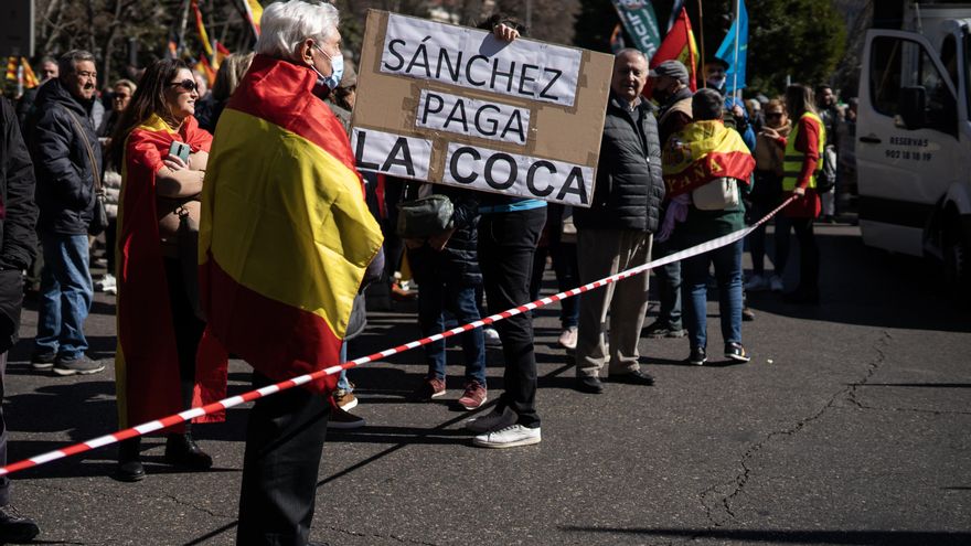 Un hombre arropado con una bandera de España y una pancarta contra Pedro Sánchez en la manifestación de este sábado.