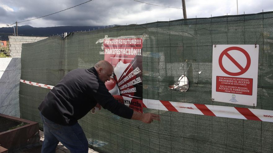 Marcelino Rodríguez cuelga en La Laguna un cartel que anuncia la manifestación convocada este viernes para exigir soluciones inmediatas para los damnificados por el volcán de La Palma