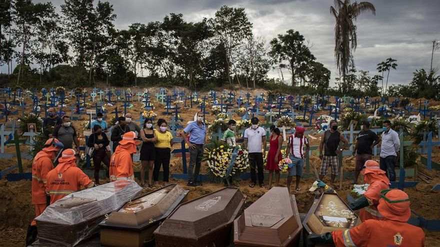 Un grupo de personas asiste a un sepelio en una tumba colectiva, en un área abierta en el cementerio Nossa Senhora Aparecida, ubicado en la ciudad de Manaos, Amazonas. La nueva sección del cementerio se abrió después de las muertes causadas por COVID-19 que colapsaron el sistema funerario de la ciudad.