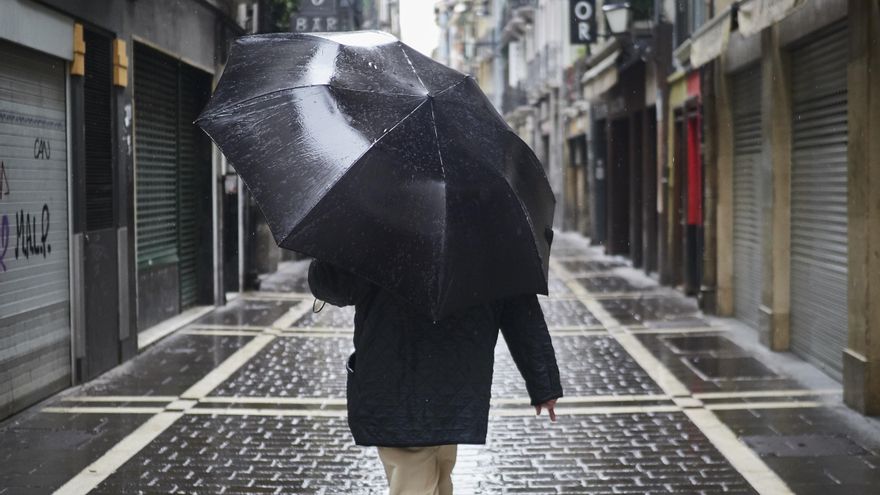 Archivo - Un hombre camina protegiéndose con un paraguas por la lluvia por el casco viejo de Pamplona.