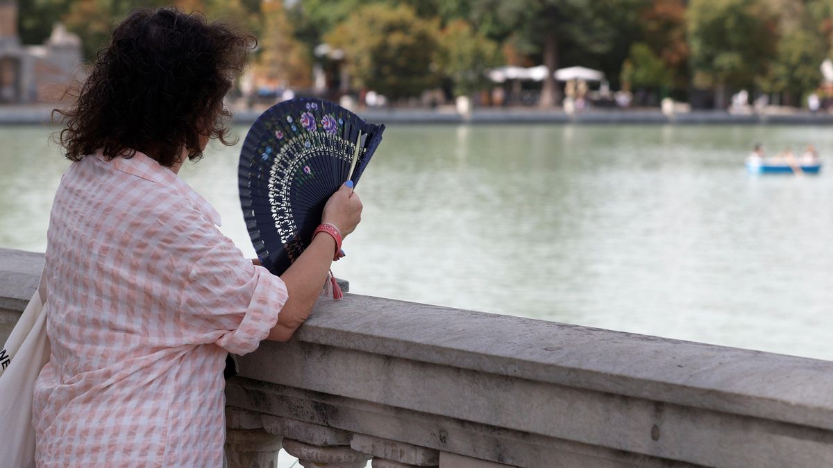 Una mujer combate el calor con un abanico mientras observa el lago del Parque del Retiro de Madrid en imagen de archivo.