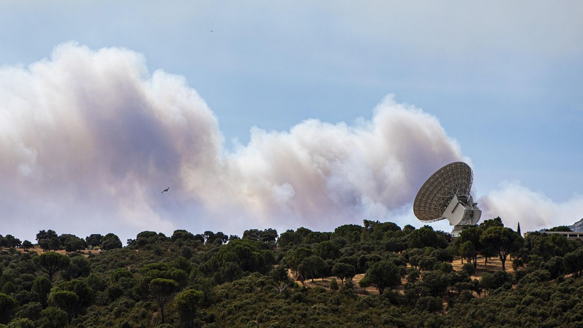 El humo de un fuego cercano sobrevuela una antena de la NASA, a 24 de julio de 2026, en Robledo de Chavela, Madrid (España). Los incendios que afectan a la Comunidad de Madrid siguen avanzando sin control y se han unido en un solo foco, mientras que en Áv