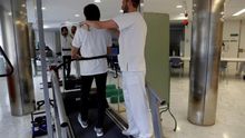 Un paciente que se recupera de un ictus realiza un ejercicio de rehabilitación de fisioterapia , ayudado por un fisioterapeuta, en un Hospital de Día de Neurorehabilitación.