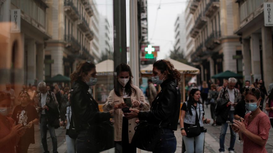 Una empleada escanea el certificado de vacunación de una cliente a la entrada de una tienda en Atenas.