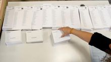 Una persona coloca las listas con las diferentes candidaturas que concurren a las elecciones generales que se celebran mañana durante el montaje del colegio electoral en el CEIP Pi i Margall de Madrid.