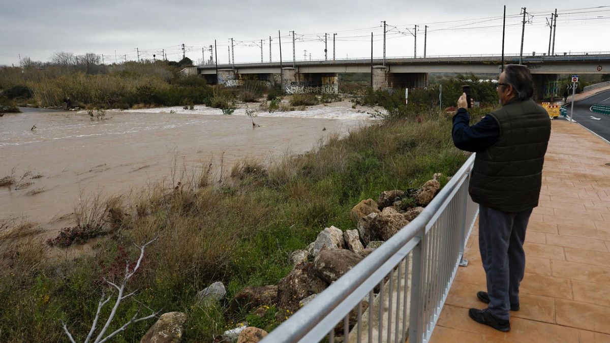 Una persona toma una imagen del caudal del río Palancia a su paso por Sagunto, este martes.