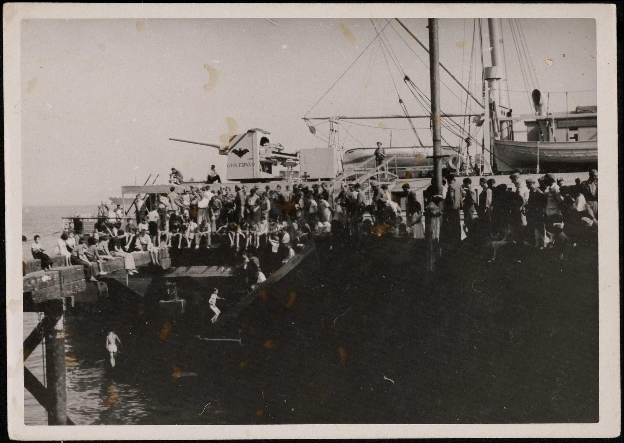 "La normalidad ya absoluta permite a los chicos esos baños en el puerto bajo los muelles donde numeroso público se congrega. El Ciudad de Valencia y otro de carga en el puerto ya abierto". 30 de agosto de 1937 | Biblioteca Nacional de España