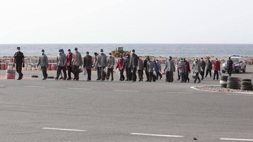 Un grupo de personas custodiadas por la Policía Nacional en el Circuito de Maspalomas tras llegar en patera al sur de Gran Canaria.