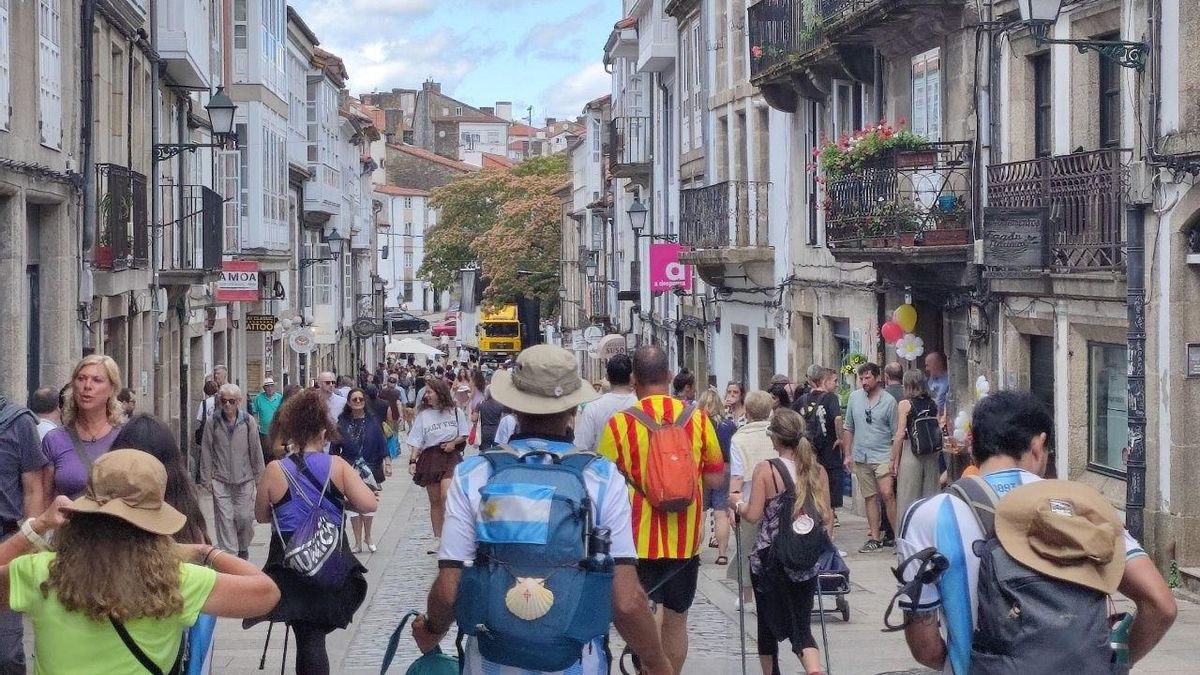 Peregrinos discurren por las calles de Santiago de Compostela. En primer plano, dos de ellos ataviados con la camiseta de la selección de Argentina.