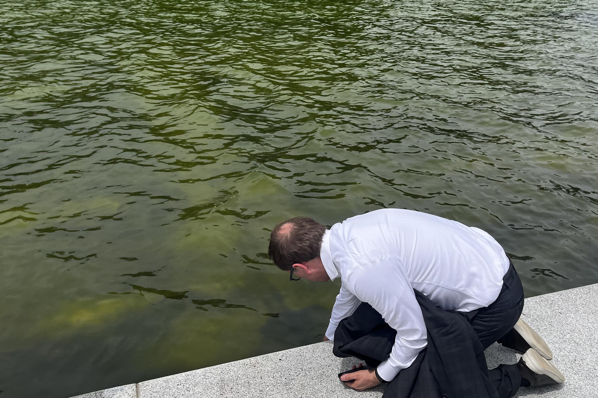 Una persona fue captada este 18 de junio al revisar el agua del estanque reflectante de la capital estadounidense, que ha vuelto a teñirse de verde por la repoblación de algas acuáticas, en Washington DC (EE.UU.). EFE/Leonor Trinidad