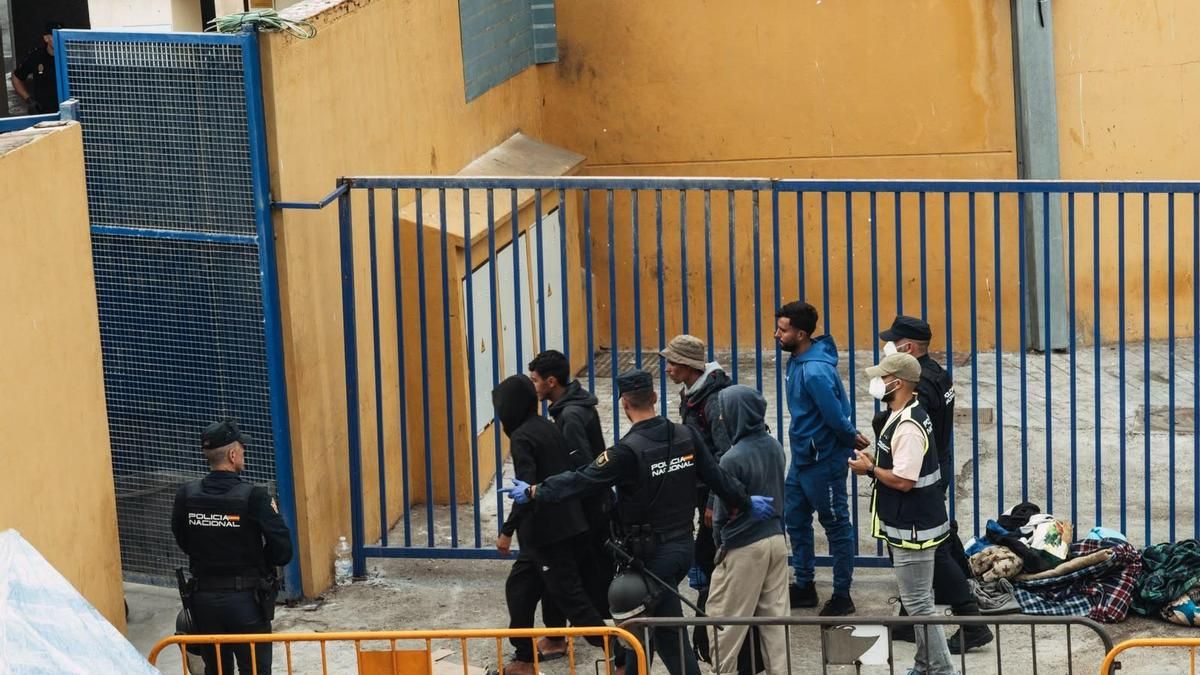 Un agente indica a un grupo de migrantes que salgan por la puerta que conecta las naves del Tarajal con la frontera, después reunirse con ellos antes de ser identificados para animarles a que fuesen retornados "voluntariamente".