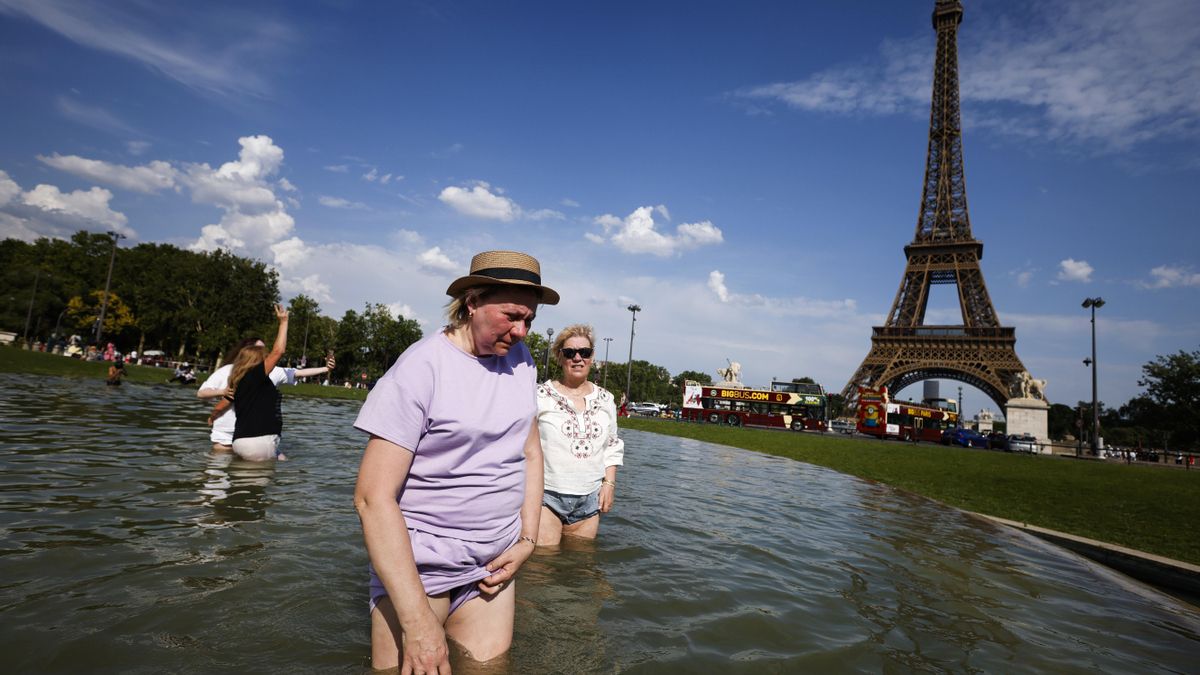 La gente se refresca en la fuente del Trocadero, junto a la Torre Eiffel, en París.
