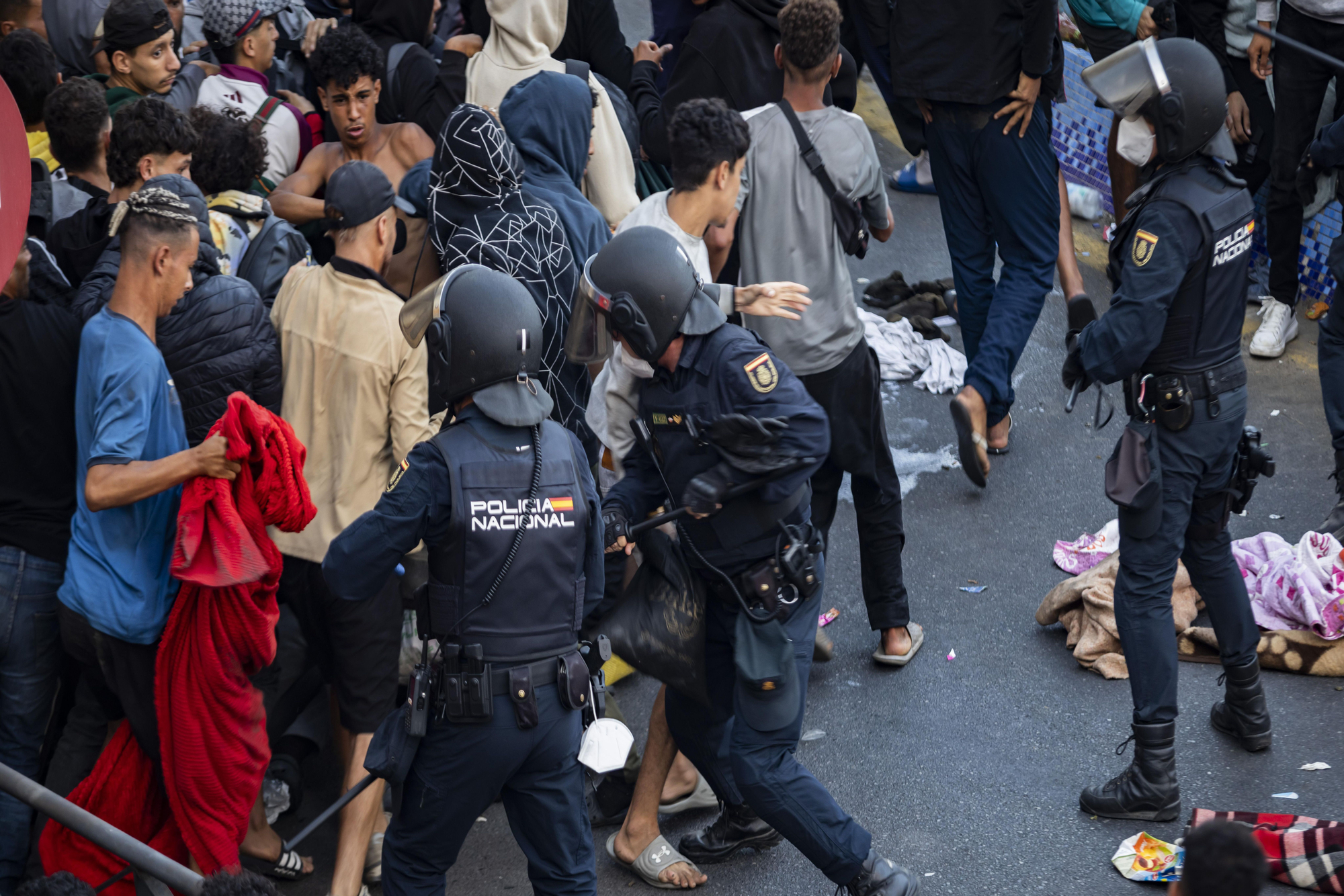 Un agente carga contra un grupo de migrantes de los cientos que esperan para avanzar hacia el puerto.