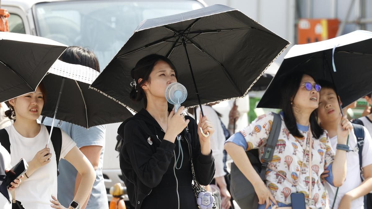 Peatones usan sombrillas para protegerse del sol en medio de altas temperaturas en Tokio, este miércoles.