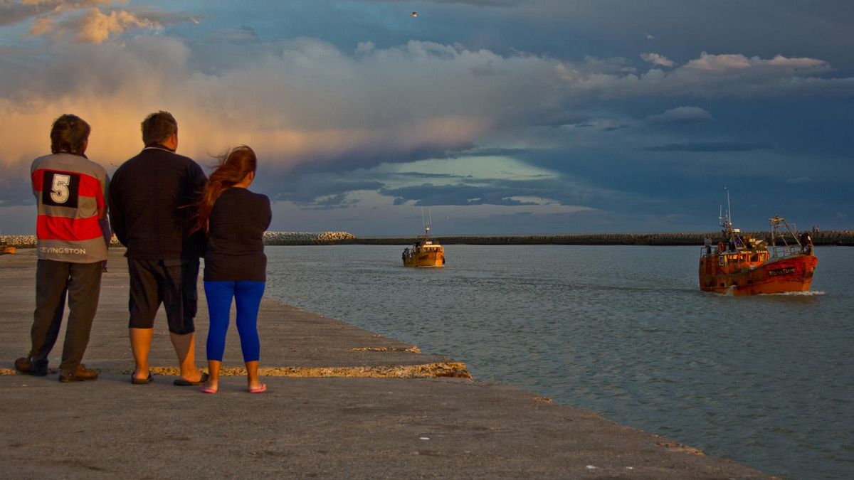Varios familiares esperan el regreso de la flota pesquera en Puerto Rawson.