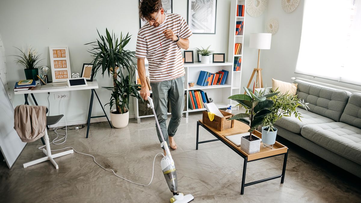 Joven utilizando la aspiradora en su salón