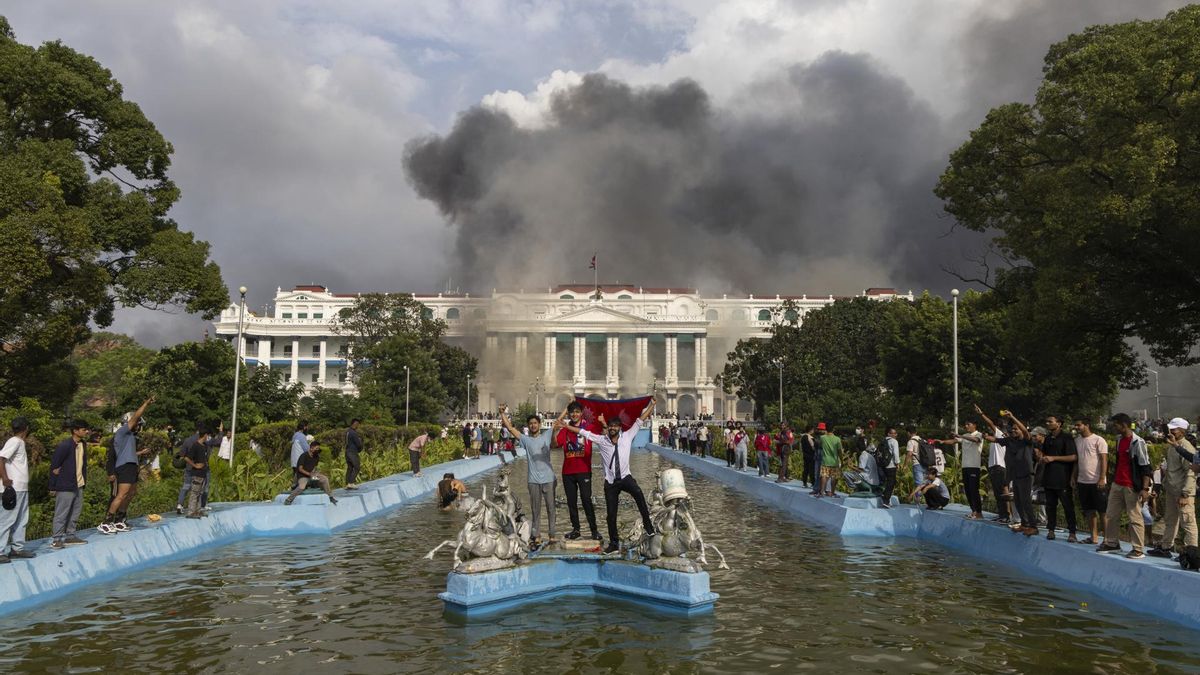 Manifestantes frente al palacio Singha Durbar en llamas, sede del gobierno y del parlamento