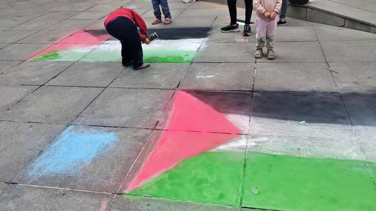 Niñas pintando con spray de tiza banderas palestinas frente al colegio Pi i Margall