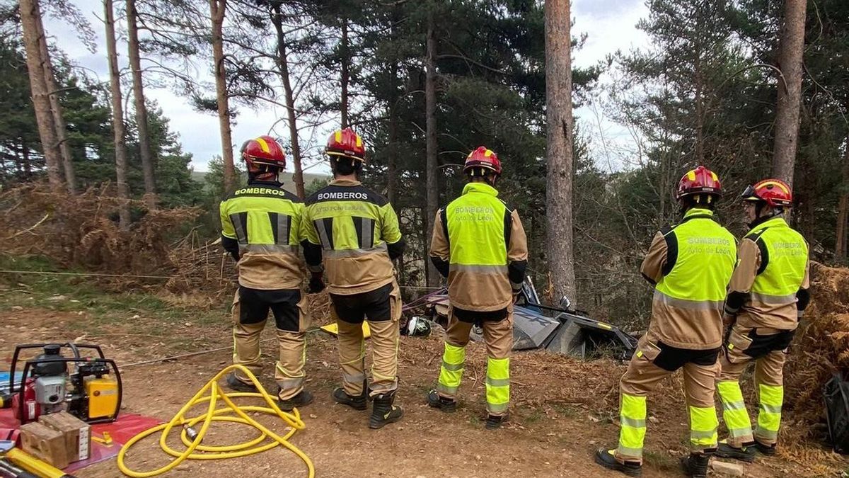 Los Bomberos junto al vehículo accidentado en la pista forestal de Foncebadón.