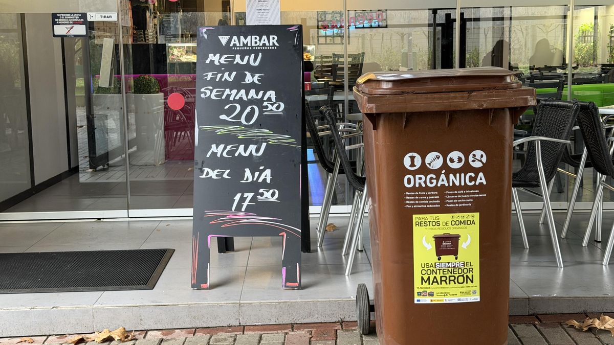 Contenedor marrón frente a un establecimiento