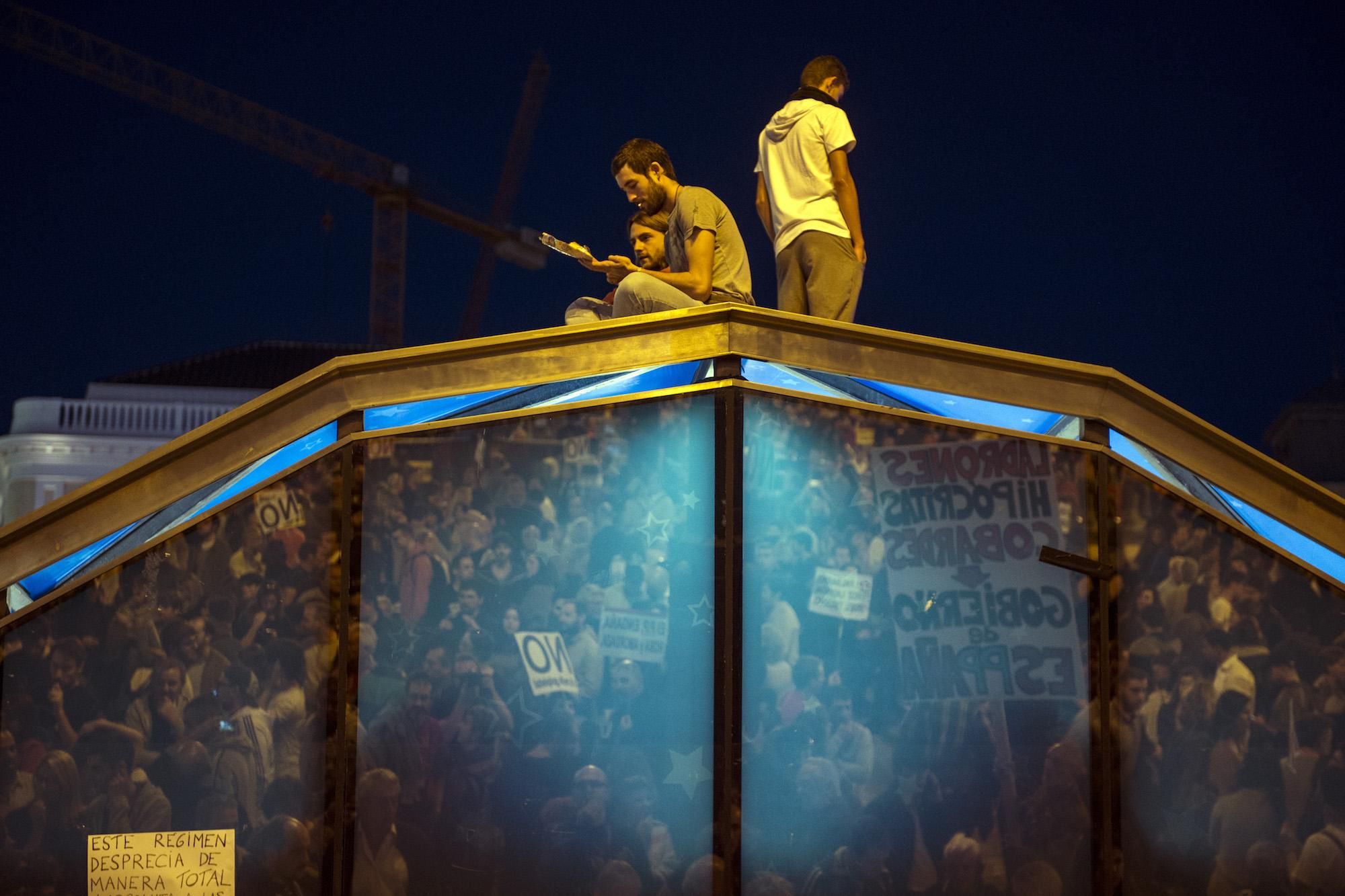 Tres manifestantes se encaraman a la cúpula de entrada y salida al Metro de Sol, al finalizar la manifestación "rodea el Congreso"