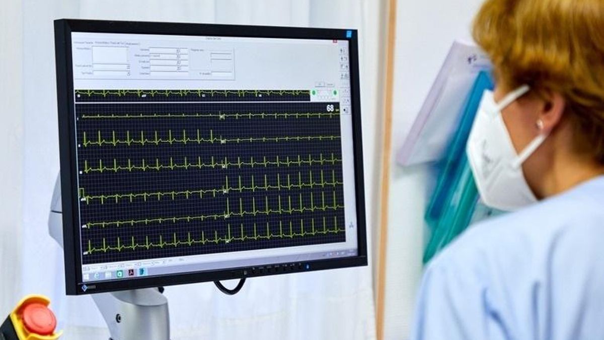 Una sanitaria observa un electrocardiograma