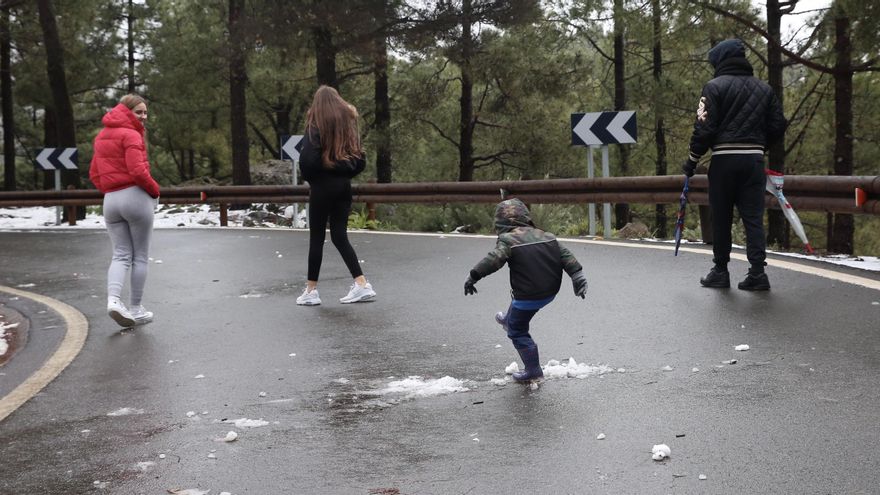 Un niño juega con la nieve en el asfalto