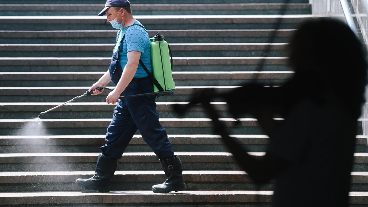 Un trabajador desinfecta una escalera en un edificio público en Moscú