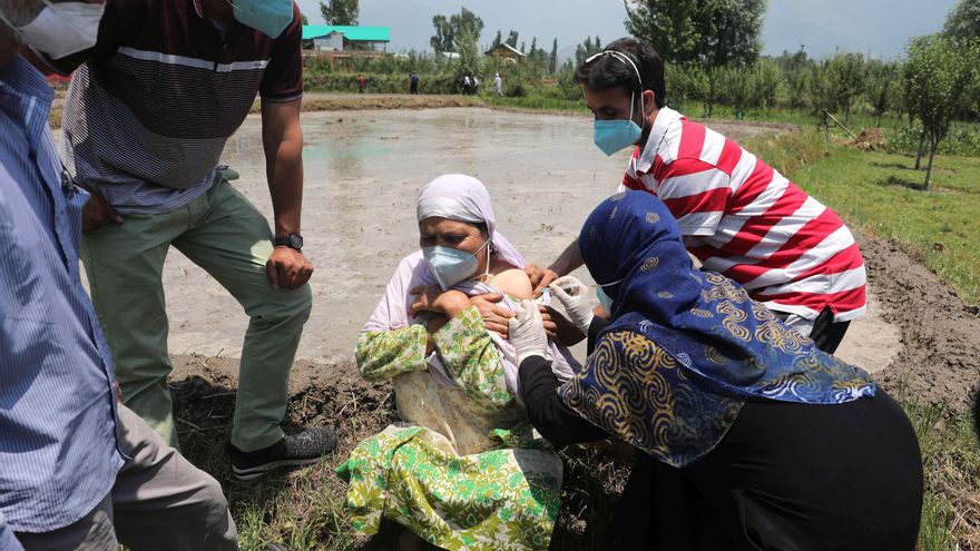 Una mujer es vacunada contra la covid-19, en un pueblo cercano a Srinagar, capital de verano de la Cachemira india. El gobierno ha comenzado la vacunación puerta por puerta de sus vecinos para tratar de detener el avance del virus. EFE/ Farooq Khan