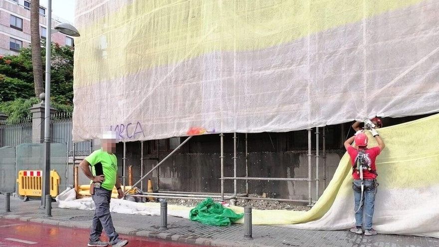 Los operarios retiran a parte de la lona utilizada para el mensaje antifascista