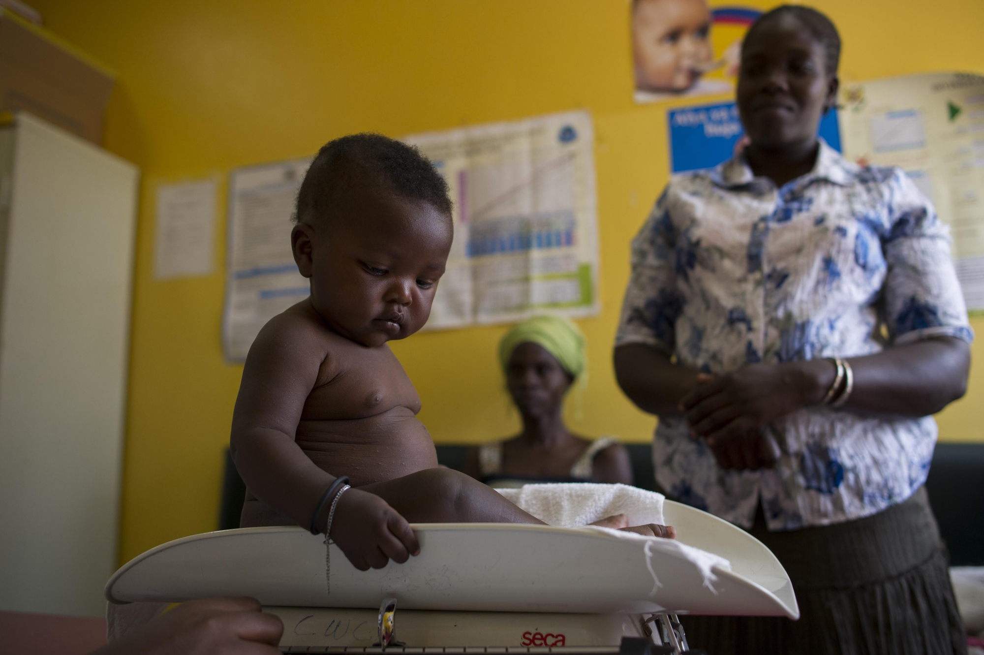 Simon Otieno, de apenas cinco meses, sano y robusto, curiosea la báscula en la que se comprueba su peso. Cada semana, nacen 45 bebés en el centro. Dado que muchos de los habitantes de Kibera viven con VIH, la clínica proporciona cuidados a los recién nacidos para prevenir que contraigan el virus de sus madres. Fotografía: Phil Moore