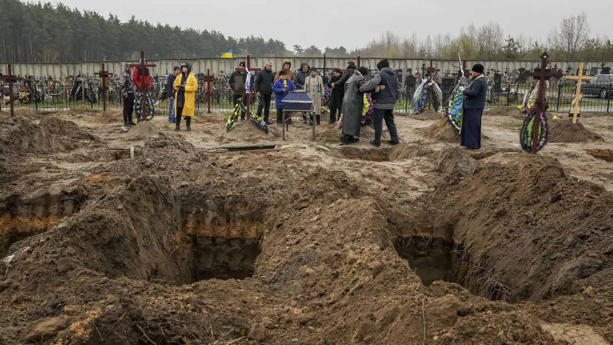 Varias personas asisten a un entierro en el cementerio de Bucha (Ucrania).