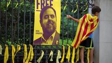 Un joven con una estelada al cuello escala una reja con un cartel que pide la libertad de Junqueras