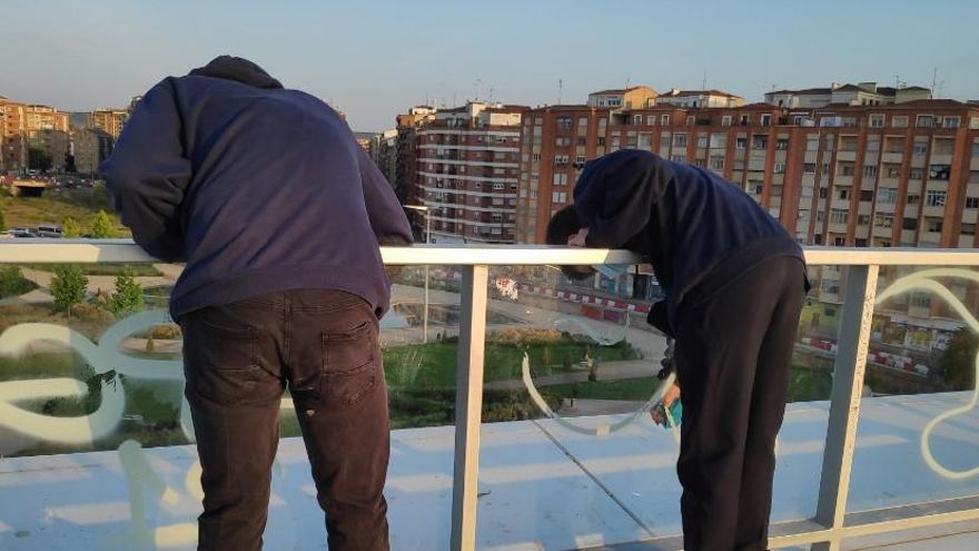 Dos jóvenes limpian grafitis en el entorno del Parque Felipe VI