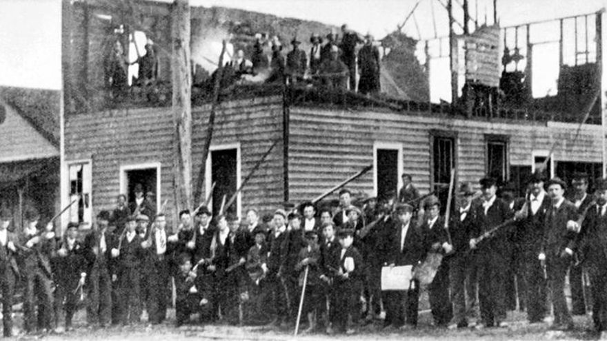 Un grupo de hombres armados posa ante los restos del diario Daily Record, incendiado tras la masacre del 10 de noviembre de 1898