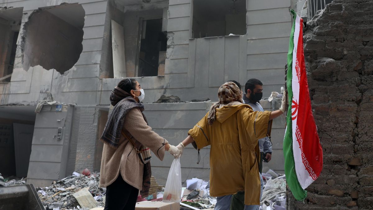 Dos hermanas iraníes se dan la mano frente a un edificio dañado en el sur de Teherán, Irán, el 15 de marzo de 2026. EFE/EPA/ABEDIN TAHERKENAREH